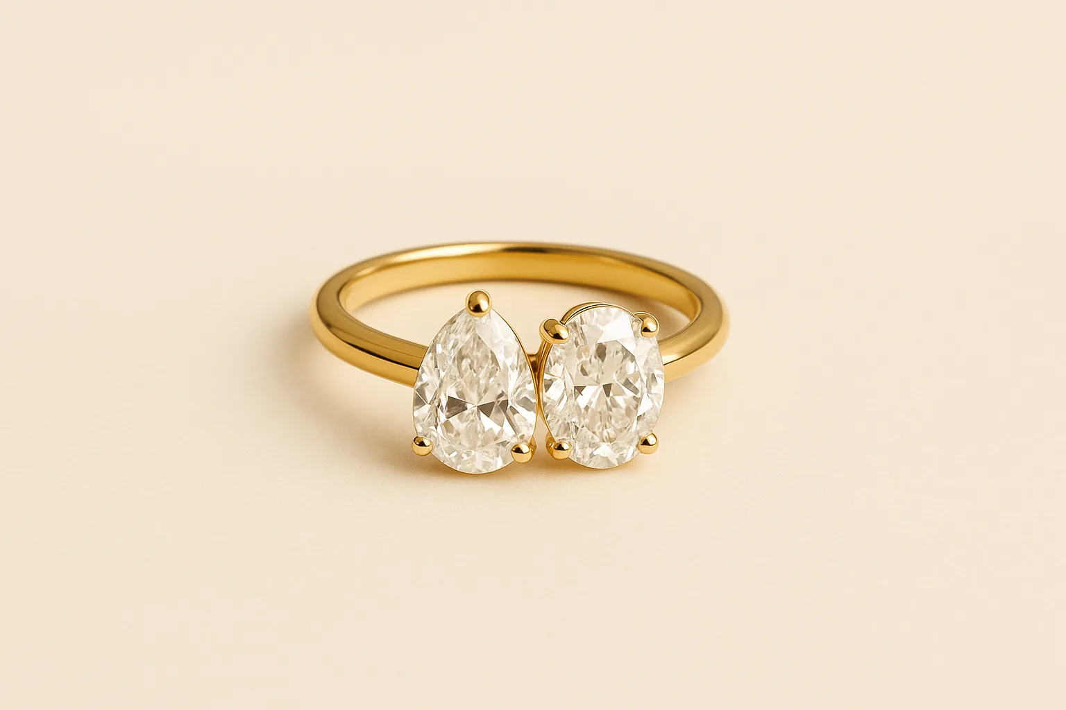 A yellow gold ring set with two diamonds side by side, a pear shape and an oval of matching size, touching at the top of the band.